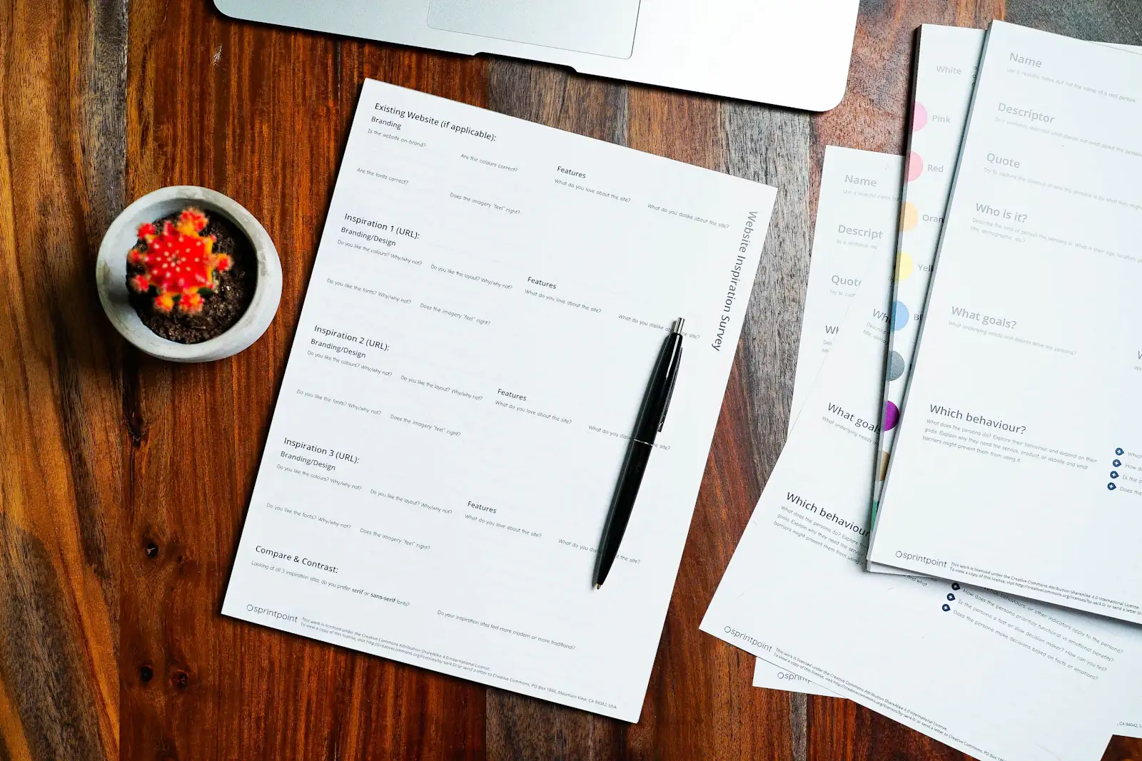 Printed documents and a pen laid out on a wooden desk