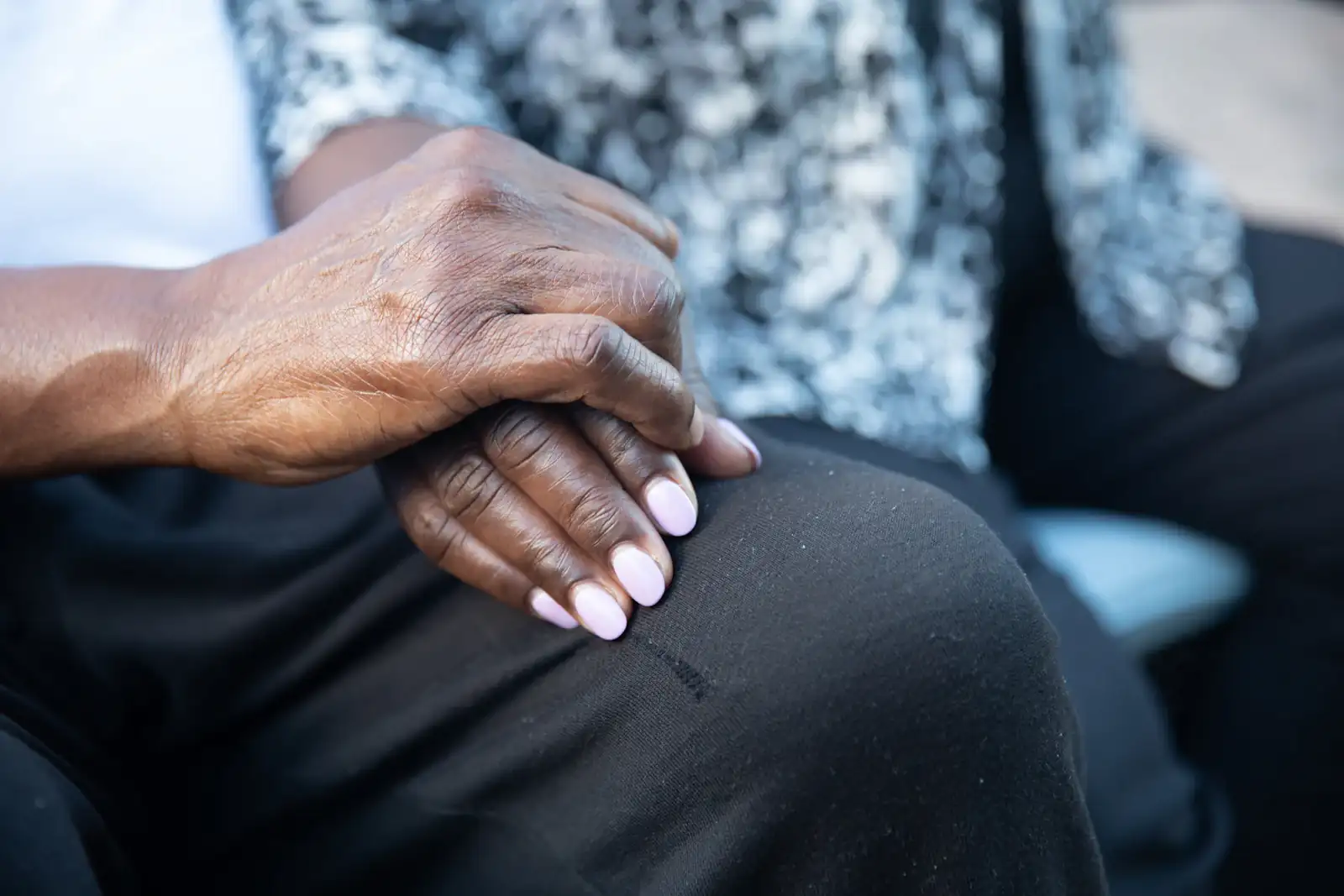 Close-up of a supportive hand resting on an older person's hand